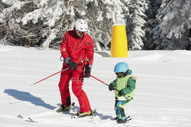 Ski class with male instructor and little boy in snowy mountains. — Stock Photo