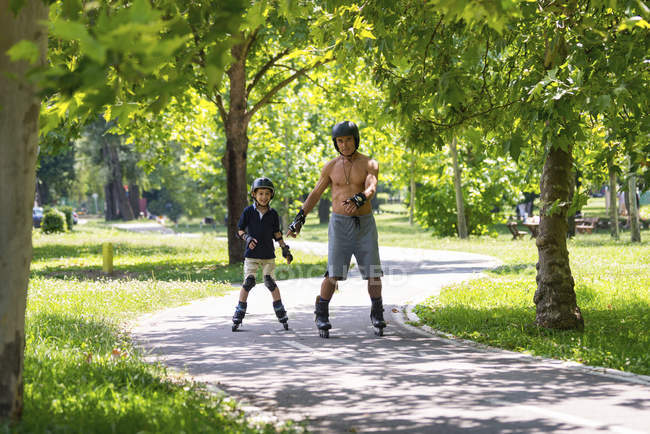 Grand-père et petit-fils aiment patiner dans le parc . — Photo de stock