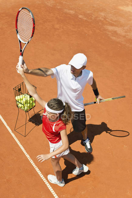Entraîneur avec un joueur de tennis adolescent pratiquant le service . — Photo de stock