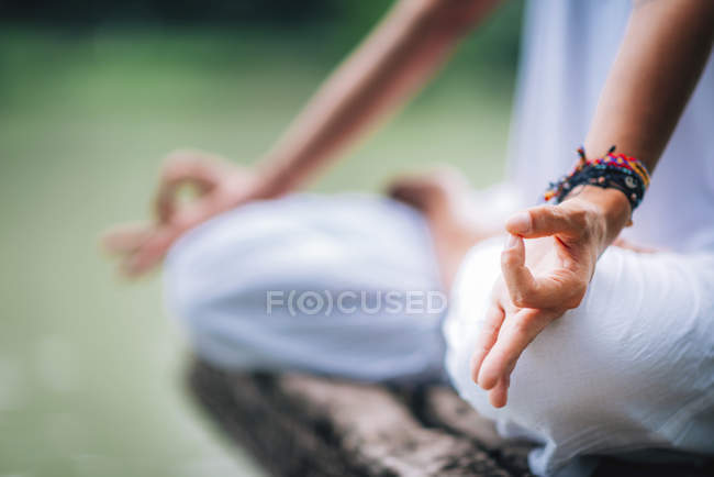 Primer plano de las manos femeninas en mudra de mujer en posición de loto por lago . - foto de stock