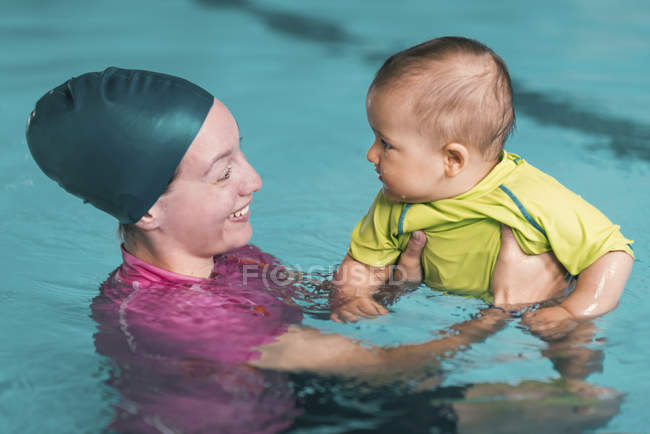 Инструктор-женщина держит мальчика с классом плавания — стоковое фото