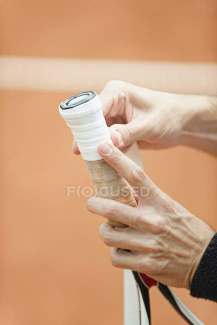 Primo piano delle mani del giocatore che avvolgono il nuovo nastro adesivo sulla racchetta da tennis . — Foto stock