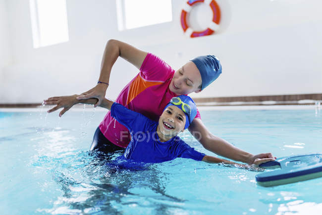 Menino aprendendo a nadar com instrutora feminina na piscina . — Fotografia de Stock