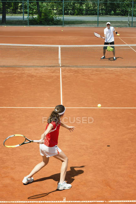 Teenie-Tennisspielerin im Training mit Trainer übt Vorhand. — Stockfoto