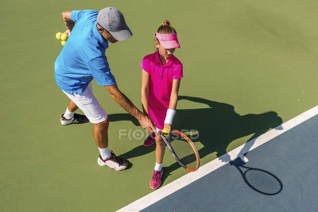 Adolescente em treinamento de tênis na quadra com instrutor masculino . — Fotografia de Stock