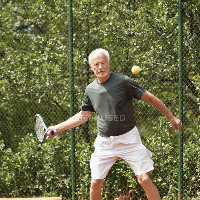 Jogador sênior masculino praticando tênis na quadra . — Fotografia de Stock