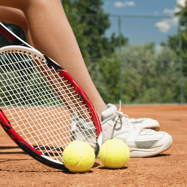 Füße einer Tennisspielerin in der Pause mit Tennisschuhen, Schläger und Bällen. — Stockfoto
