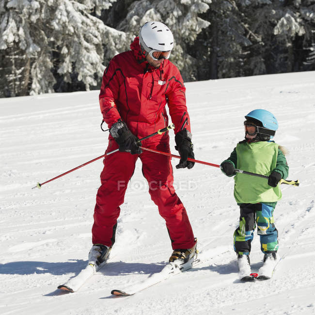 Niño preescolar esquiando con instructor masculino . - foto de stock