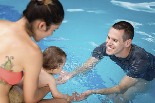 Bebé entrando en el agua de la piscina por primera vez
. - foto de stock