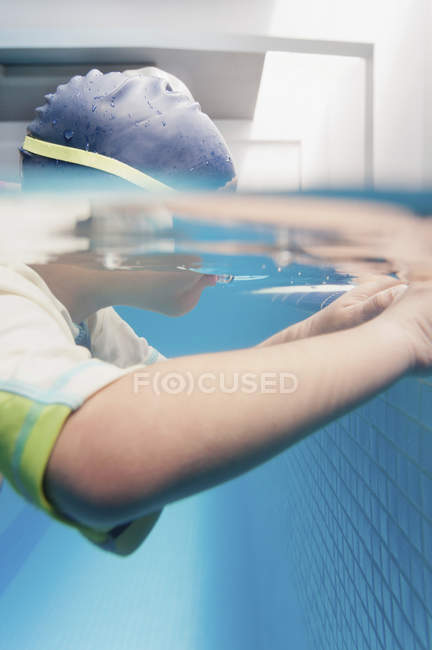 Unterwasser-Ansicht eines Kindes im Schwimmkurs, das sich am Beckenrand festhält. — Stockfoto