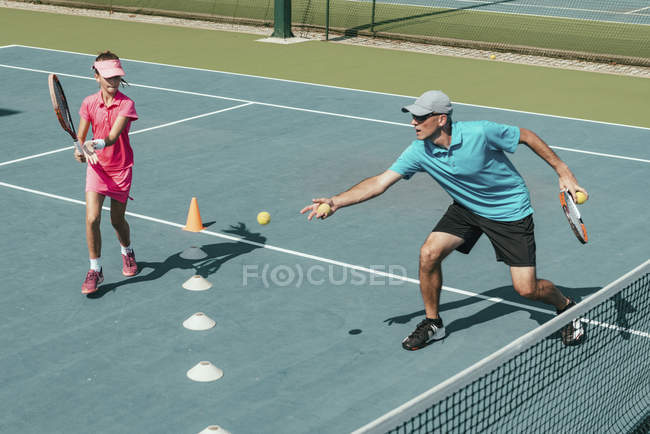 Instructeur de tennis masculin entraînement adolescent joueuse sur le terrain . — Photo de stock