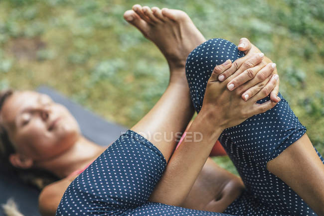 Молодая женщина, занимающаяся йогой, деталь из лежащей позиции с избирательным фокусом на руках . — стоковое фото