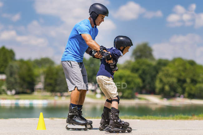 Clase de patinaje sobre ruedas con profesor senior y niño de edad elemental . - foto de stock