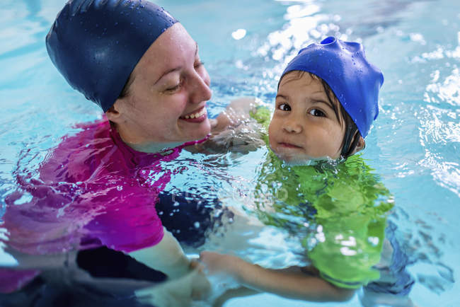 Bambino che impara a nuotare con istruttrice femminile in piscina . — Foto stock