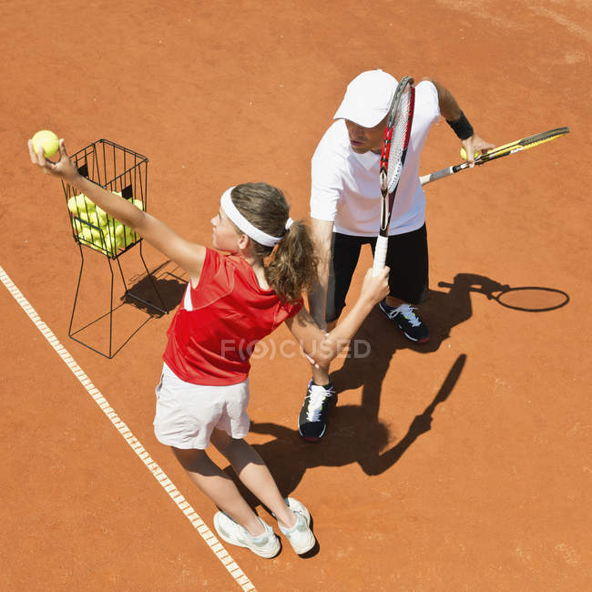 Adolescente tenista praticar servindo com treinador . — Fotografia de Stock