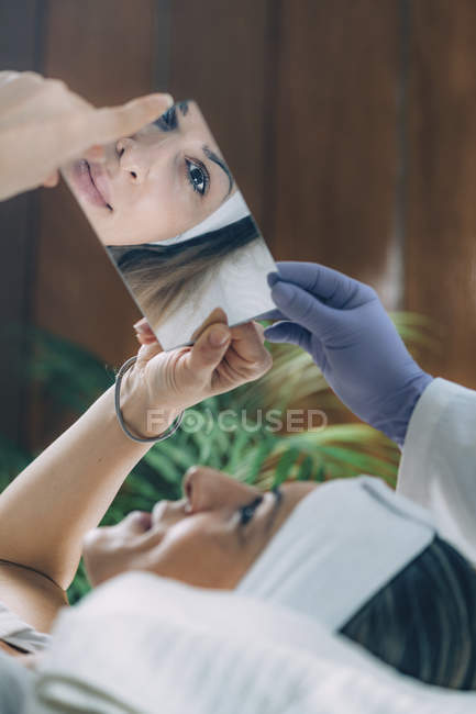 Satisfied woman after lash lifting procedure looking into mirror — Stock Photo