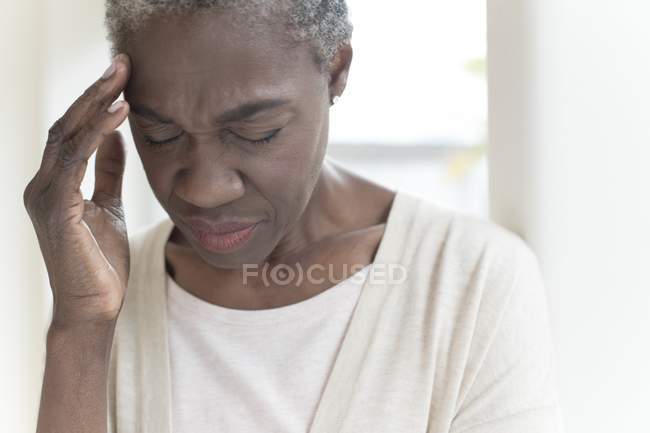Mature woman touching head in pain with hand. — Stock Photo