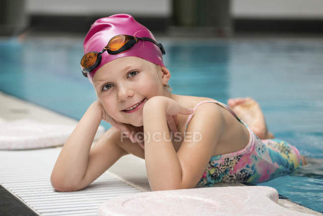 Cute little girl posing on swimming pool edge. — Stock Photo