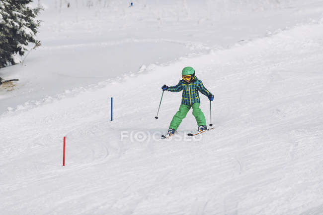 Маленький хлопчик в зимовому одязі катається на лижах на засніжених горах . — стокове фото
