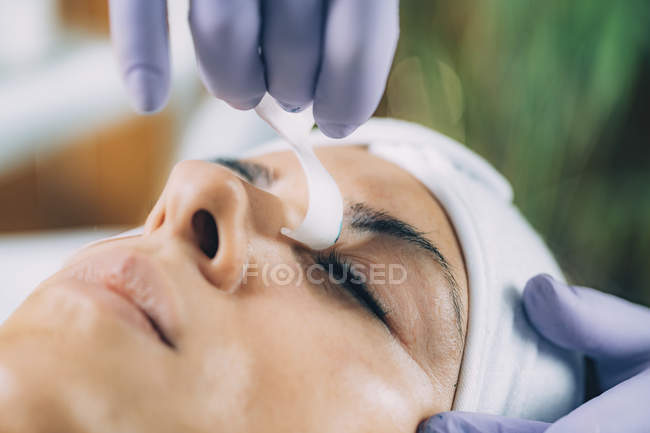 Cosmetólogo limpiando los ojos de la mujer después del procedimiento de levantamiento de pestañas - foto de stock