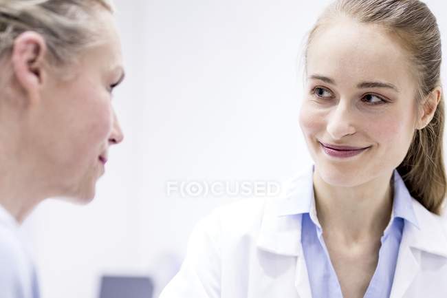 Ärztin lächelt Patientin während Konsultation an. — Stockfoto