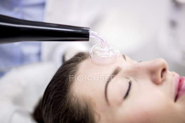 Молода жінка отримує косметичні процедури з використанням високочастотної машини в клініці. — стокове фото