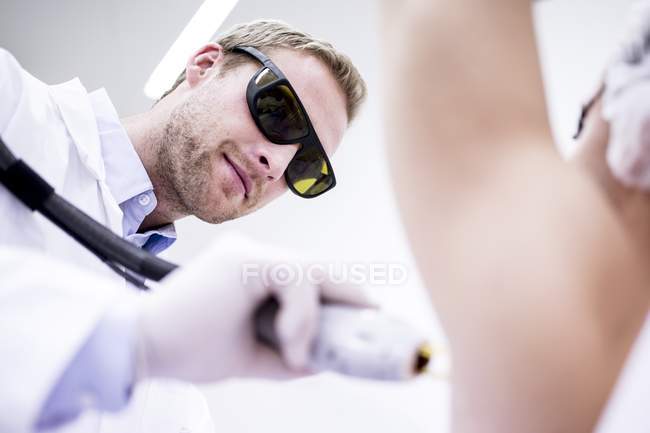 Dermatologue utilisant un traitement d'épilation au laser pour les aisselles féminines
. — Photo de stock