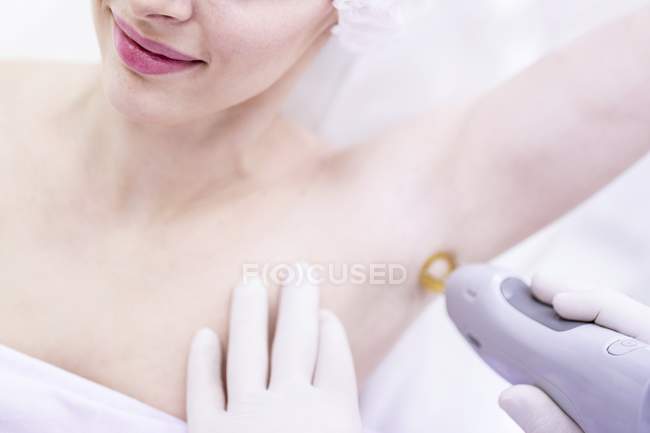 Mujer joven recibiendo tratamiento de electrólisis para axila . - foto de stock
