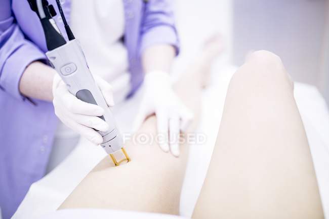 Woman getting laser hair removal treatment on leg, close-up. — Stock Photo