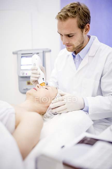 Dermatologist giving thermage treatment to mature woman face to softening wrinkles. — Stock Photo