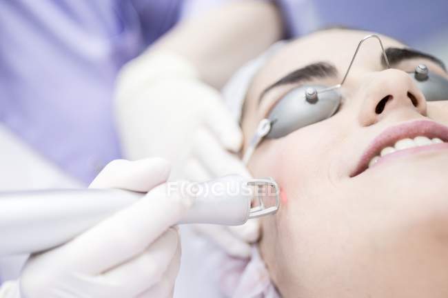 Dermatologe mit Laserschweißgerät auf weiblichem Gesicht. — Stockfoto