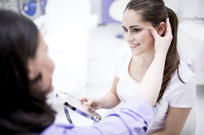 Dermatologista examinando a pele facial do paciente . — Fotografia de Stock