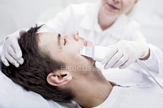 Dermatólogo aplicando tratamiento de microdermoabrasión facial en el hombre en la clínica, primer plano
. - foto de stock