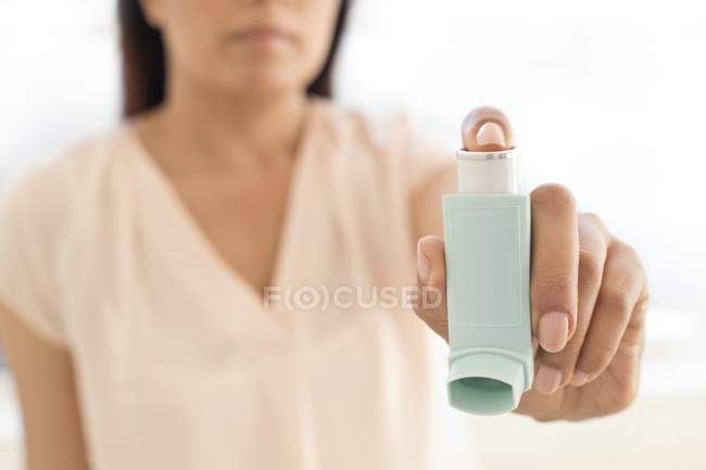 Recorte de inyección de mujer que sostiene el dispositivo inhalador . - foto de stock