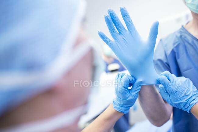 Luva cirúrgica sendo colocada na mão de um cirurgião antes da cirurgia. — Fotografia de Stock