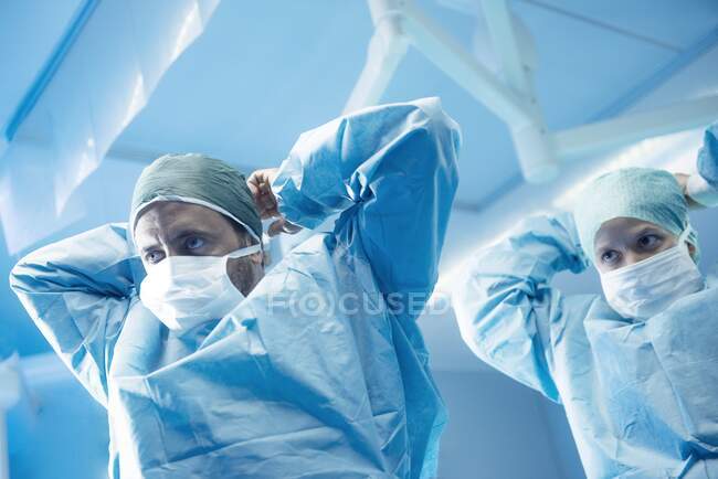 Cirurgiões vestindo-se em sala de operações. — Fotografia de Stock