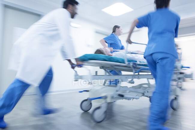 Больница экстренная, медицинский персонал толкает пациента на каталку. — стоковое фото