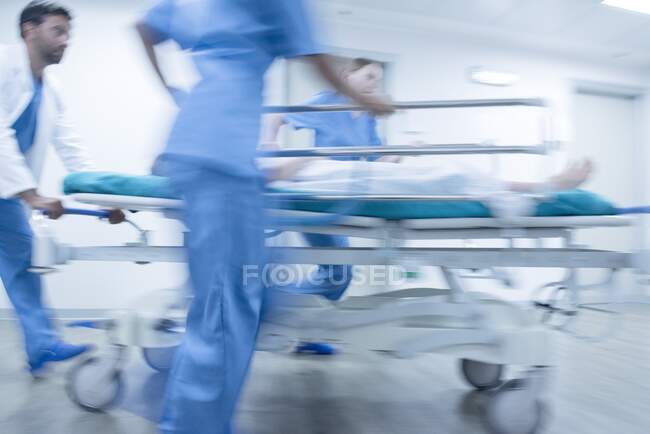 Срочно. Медицинский персонал толкает пациента на каталку. — стоковое фото