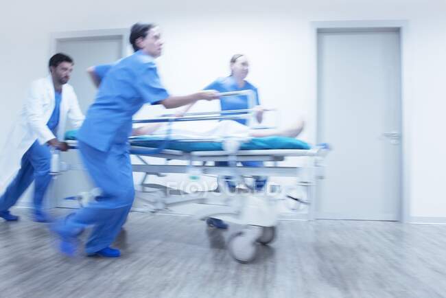 Notfall im Krankenhaus, medizinisches Personal schubst Patient auf Gurney. — Stockfoto