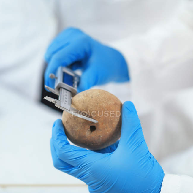 Mani di archeologo che misurano antichi manufatti in laboratorio . — Foto stock