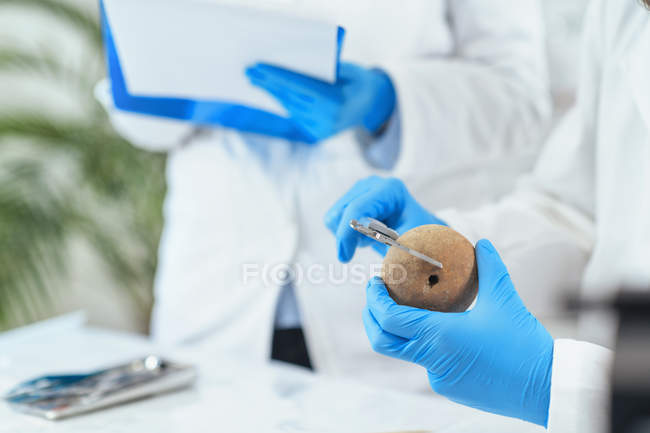 Arqueólogo masculino midiendo artefacto antiguo en laboratorio . - foto de stock