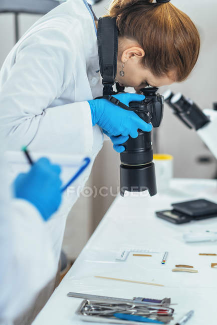 Young archaeology researcher documenting lithics with camera in laboratory. — Stock Photo