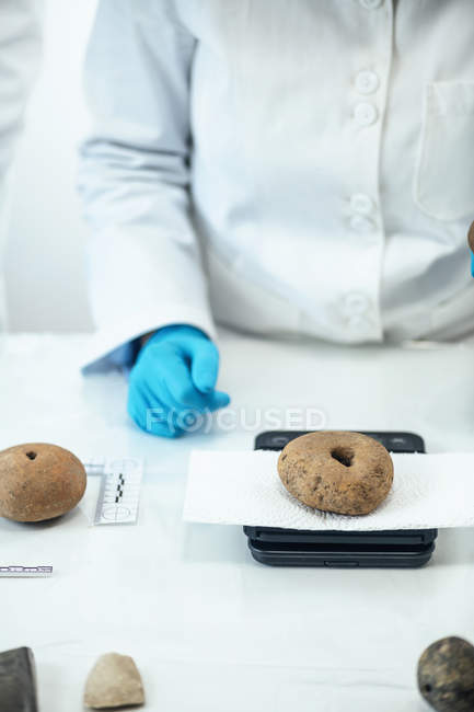 Archeologo che misura i pesi antichi del telaio su scala digitale in laboratorio . — Foto stock