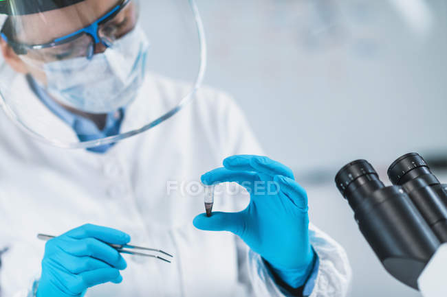 Bioarqueóloga feminina analisando micro tubo com material osteológico humano em laboratório . — Fotografia de Stock