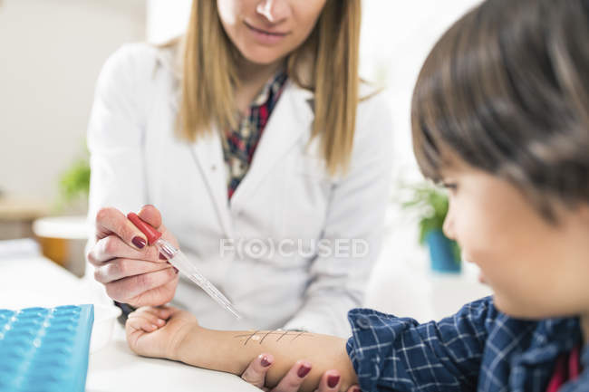 Female immunologist performing skin prick allergy testing on preschooler boy. — Stock Photo