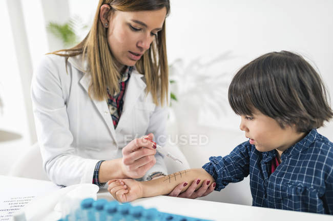 Female immunologist performing skin prick allergy testing on preschooler boy. — Stock Photo