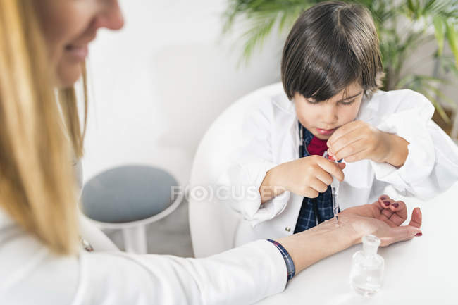 Ragazzino che gioca a essere medico in ufficio pediatra femminile . — Foto stock