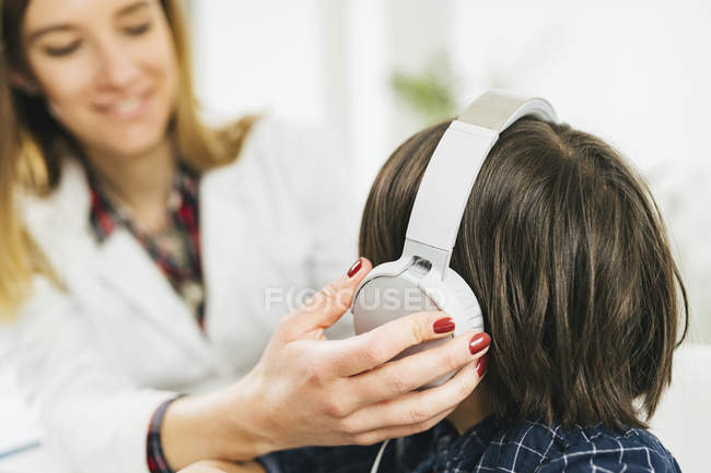 Doctora poniéndole auriculares a un chico que tiene una prueba de audición . - foto de stock