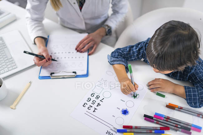 Junge färbt Formen mit bunten Stiften für entwicklungspsychologischen Test in Arztpraxis. — Stockfoto