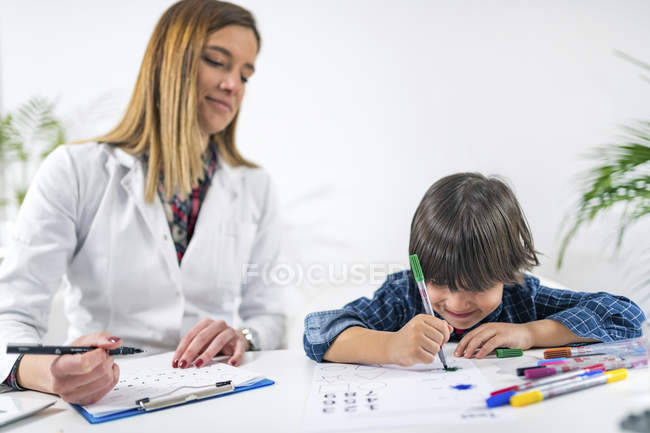 Preschooler boy coloring shapes with colorful pens for developmental psychology test in psychologist office. — Stock Photo